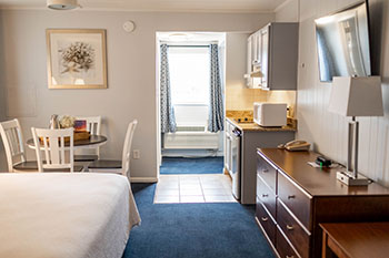 Hotel room in the Victorian showing a bed, table with chairs, and kitchenette