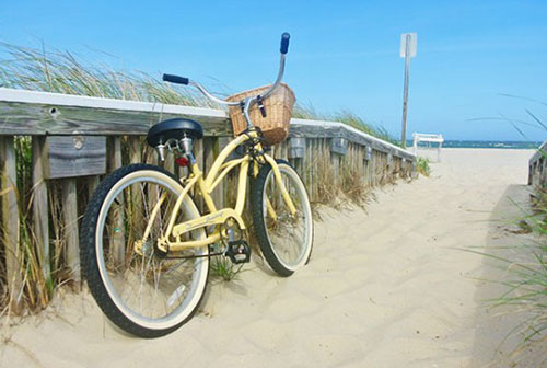 A bicycle leaning against a railing on the sand