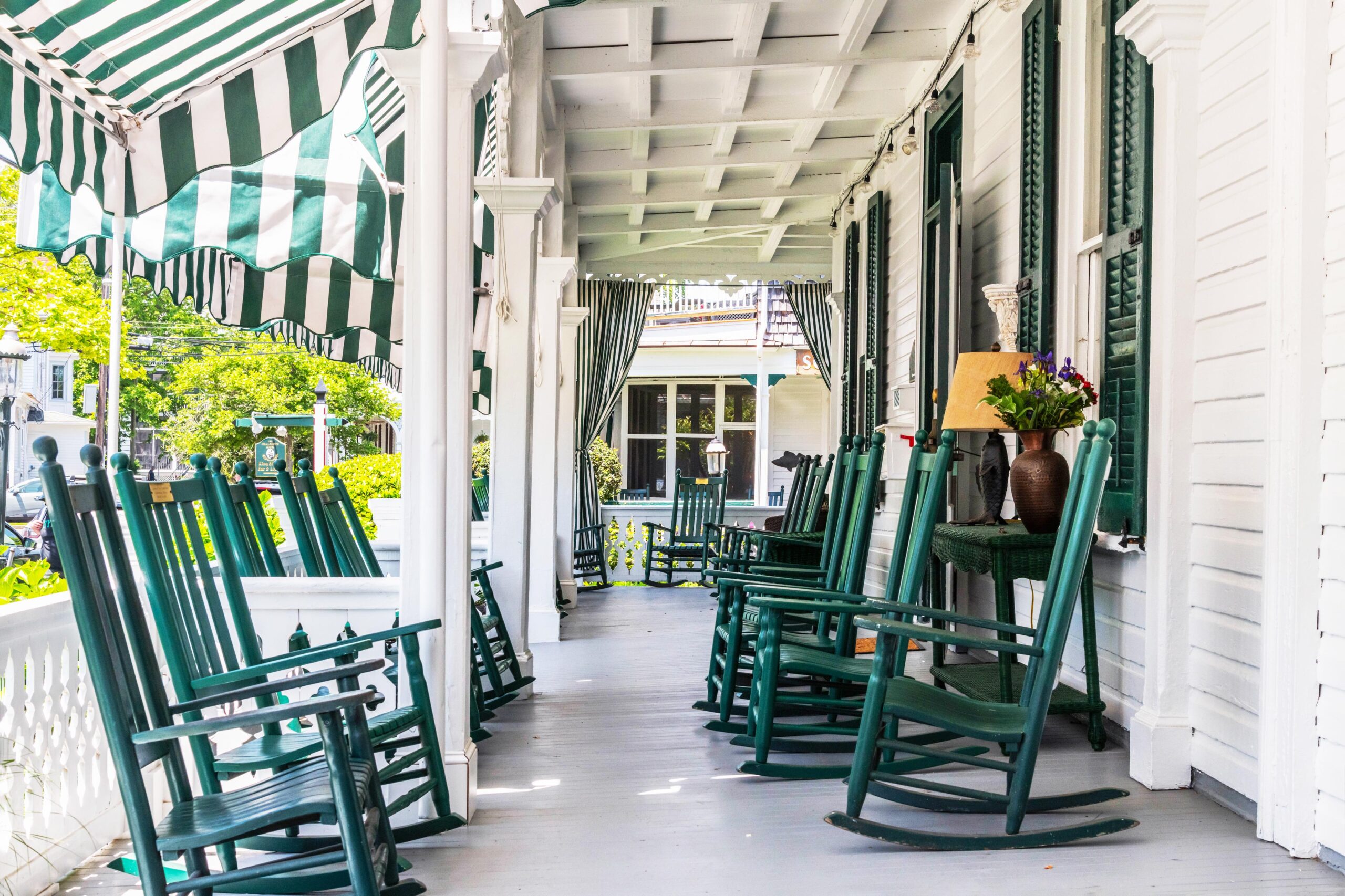 Green rocking chairs on the porch of the Chalfont Hotel on a sunny bright day.