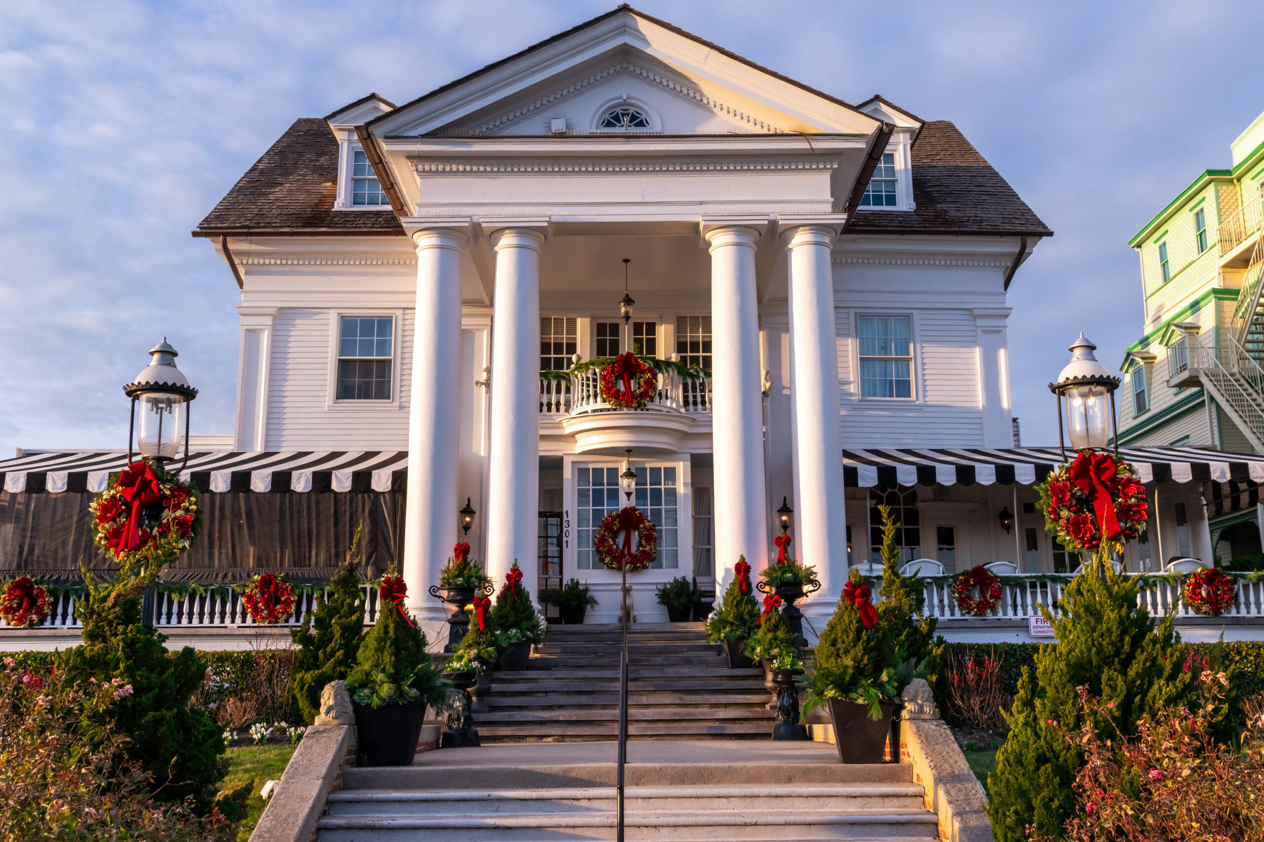 A wide view of Peter Shield's in decorated with red and green wreaths and other red and evergreen plants. The sun is shining on the building.