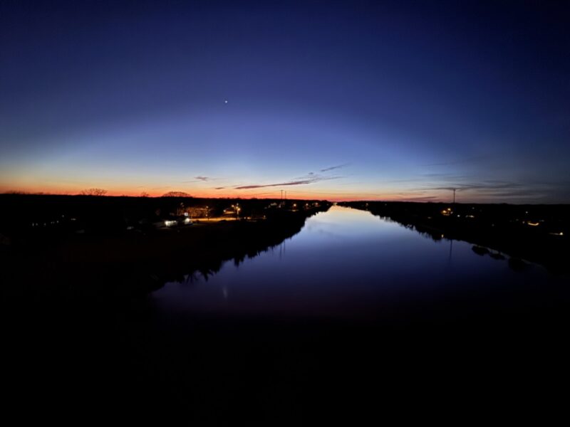 Ombre sunset in the distance, reflecting on the Cape May Canal waters, shot from the center of the West Cape May Bridge. 